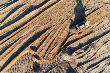 Yapım aşamasında yeni modern yolda çalışan buldozer üzerinde havadan görünümü