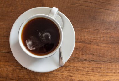 Kahverengi ahşap masanın üzerinde kahve olan beyaz fincan.