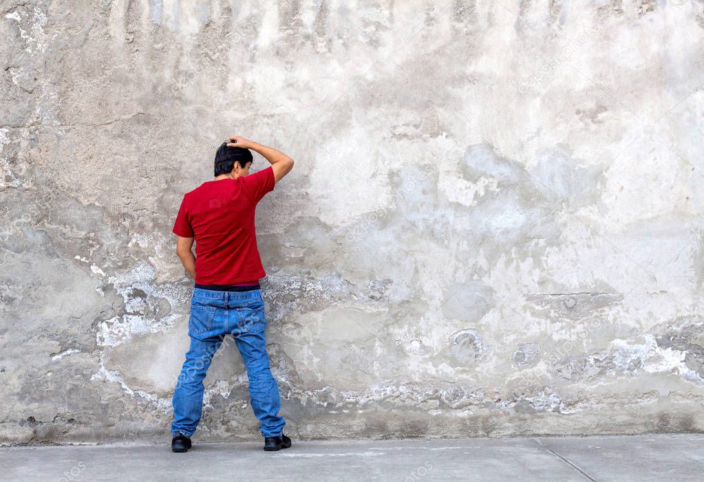 Man with red shirt peeing on a wall