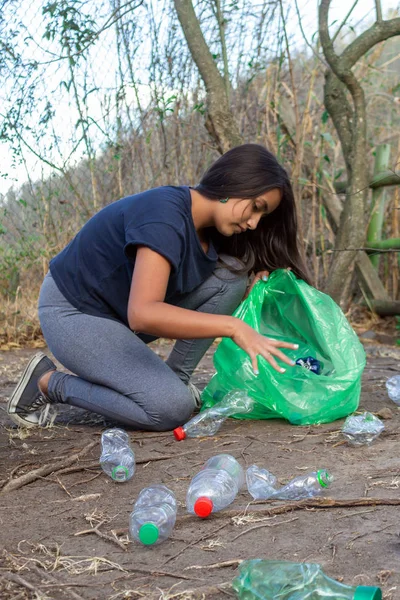 Bir ormanda plastik şişe ler toplayarak dizlerinin üzerinde kız — Stok fotoğraf