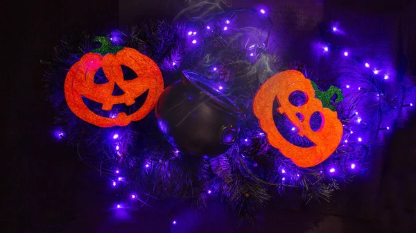 Dos calabazas de halloween con una olla negra sobre un fondo iluminado —  Fotos de Stock