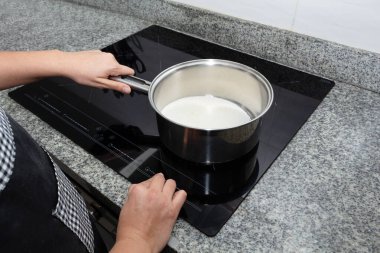 Kadın eli yakın çekim için elektrikli hob 'u çalıştırır. İşlem elmalı pasta yapar.
