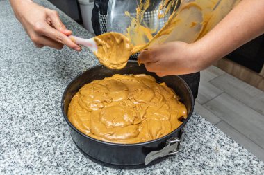 Eller bitmiş pastayı kalıba döküyor.