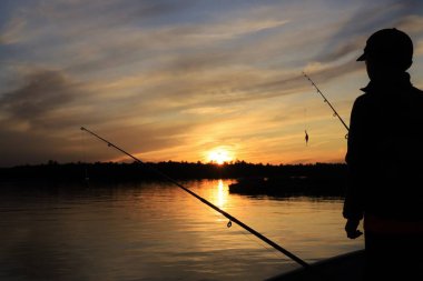 Kanada 'nın vahşi göllerinde görüldüğü gibi altın bir gökyüzüne karşı gün batımı silueti. Balıkçılık ve tatil ruhu bol, doğanın güzelliği takdir edilir ve takdir edilir. Ruhun ve aklın özgürlüğü