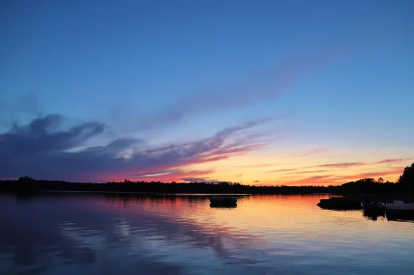 Gün batımında bulutlu gökyüzünün altındaki göl manzarası 