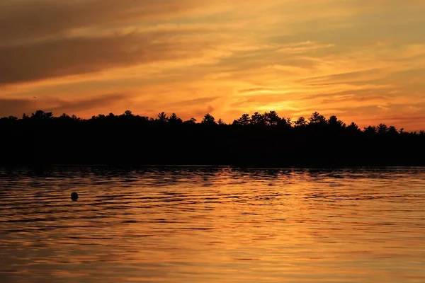 Gün batımında bulutlu gökyüzünün altındaki göl manzarası 