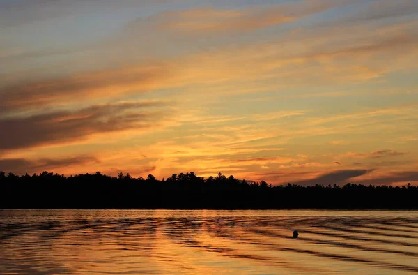 Gün batımında bulutlu gökyüzünün altındaki göl manzarası 