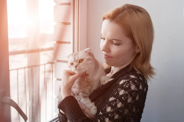 Gri bir kedi ile oynarken kızıl saçlı güzel kız