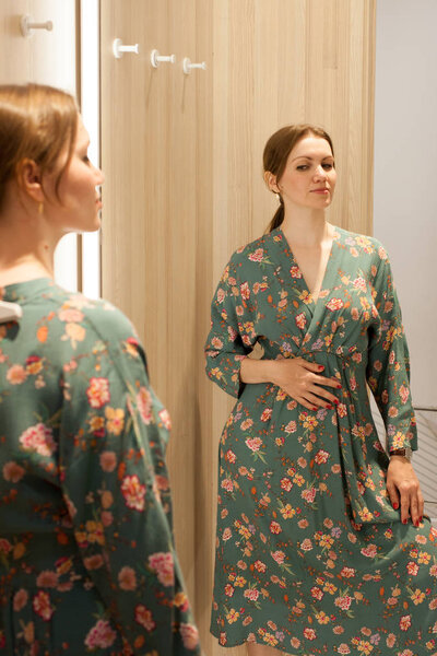 the girl tries on a new dress in a fitting-room shopping center
