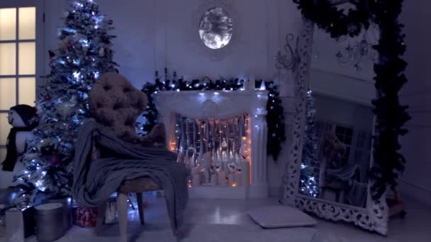 Klasický nový rok a vánoční zázemí, večerní výhled se světlem lampy, blikajícími girlandky a svíčkami na umělém krbu. Zelený strom ozdobený hračkami a míčky
