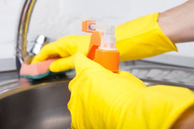 koruyucu eldiven adam ev temizliği sırasında bir sprey ve bir duster kullanarak lavabo temizler, yakın çekim