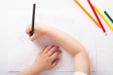 Kız renkli kalemler çizer. Üstte görüntü