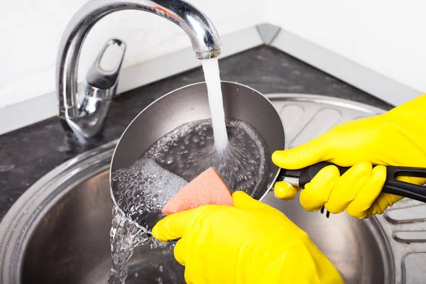キッチンでフライパンを洗浄ゴム手袋で女性の手のクローズ アップ — ストック写真