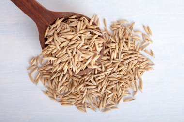 Beyaz arka plan üzerinde tahta kaşık yulaf tohumu, üst görünümü