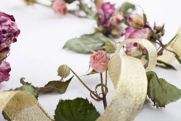 beyaz ahşap tahta arka plan üzerinde altın bir kurdele ile kurutulmuş çiçekler