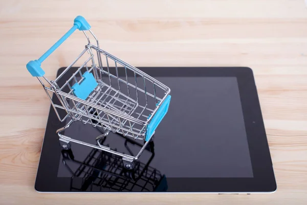 Shopping Cart over a Tablet PC on wooden table