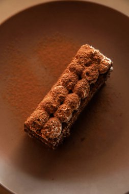 Kahverengi arka plan üzerinde Tiramisu kek. Minimal modern tatlı konsepti. Üstte görüntü