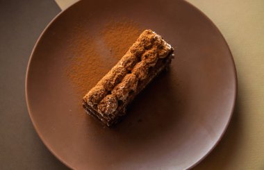 Kahverengi arka plan üzerinde Tiramisu kek. Minimal modern tatlı konsepti. Üstte görüntü
