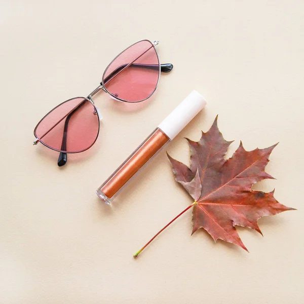 秋のファッションや美容組成物ピンクのサングラス ブロンズリップグロスや口紅やメープルリーフ 秋の概念 暖かい色と色合い フラットレイ ストックフォト