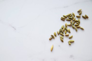 Kakule tohumları gri mermer arka planda, yakın çekim. Yeşil ve sağlıklı baharat konsepti. Yiyecek ve içecek çeşnisi. Üst görünüm ve düz uzanma