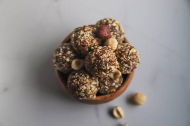 Tahta kasedeki enerji topları ev yapımı sağlıklı tatlı hurma, fındık, kuru meyve ve kakao ile pişiriliyor. Mermer arka planda organik kuru meyve atıştırmalıkları