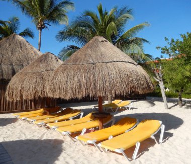 Palmiye yaprak hasır şemsiyeler ve katlanır şezlong sandalye seyahat arka plan için Cancun, Meksika, Riviera Maya üzerinde Karayip bir plajda.