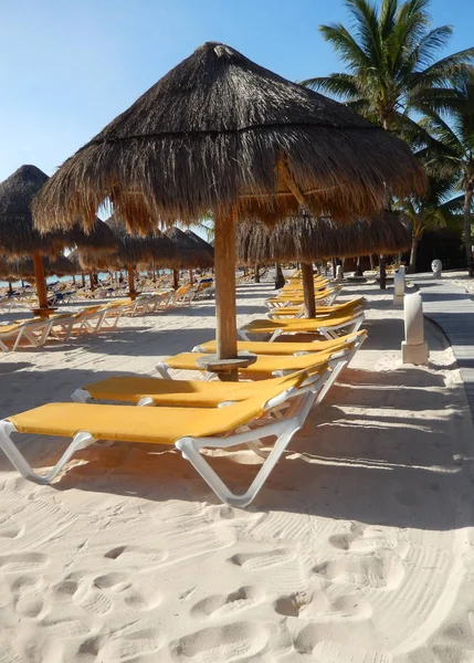 Palmiye yaprak hasır şemsiyeler ve katlanır şezlong sandalye seyahat arka plan için Cancun, Meksika, Riviera Maya üzerinde Karayip bir plajda.
