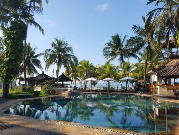 Pool and bar amenities surrounded by palm trees, in a Candidasa beach resort in Bali, Indonesia, for travel backgrounds.