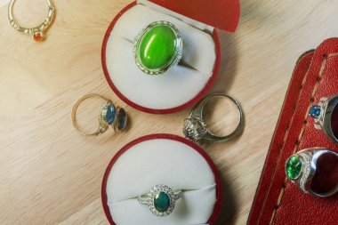 Kırmızı yüzük kutuları ile ahşap zeminler üzerine yerleştirilen değerli taş yüzük takı setleri çeşitli renklerde