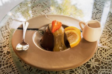 çilek krema ve dilimlenmiş portakal dilimi ile şifon çikolatalı kek bir krem renk plaka