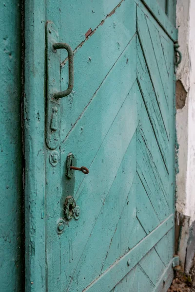 Staré dřevěné dveře vybarvené prasklou zelenou barvou. Rusty klíč v klíčové dírce. — Stock fotografie