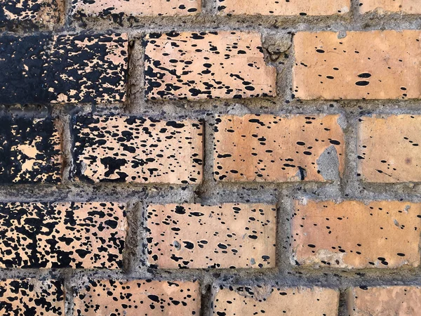 Rough peach brick wall splattered with black resin