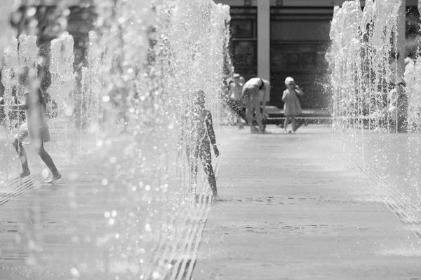 Moscovo. A Rússia. 19 de junho de 2019. Crianças tomando banho em um spray refrescante da fonte da cidade em um dia quente de verão . — Fotografia de Stock