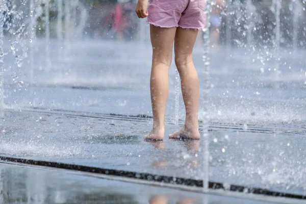 Pies desnudos para niños en un refrescante spray de la fuente de la ciudad en un caluroso día de verano —  Fotos de Stock