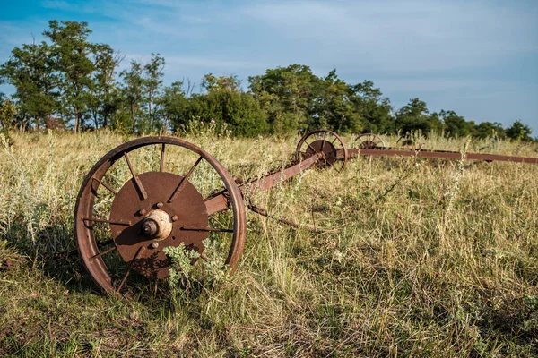 Старые ржавые колеса сельскохозяйственной техники брошены в сухой траве . — стоковое фото