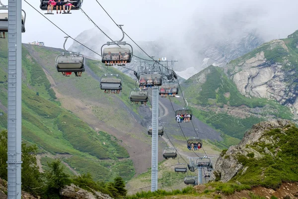 Krasnaya Polyana. Russia. July 28, 2019: Tourists climbing the mountain peaks by cable car. — Stock Photo, Image