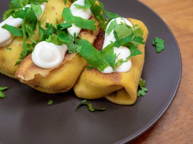 Et ile doldurulmuş ve beyaz sos ile terbiyeli ve kahverengi bir tabak üzerine maydanoz yaprakları serpilir iştah açıcı krep.