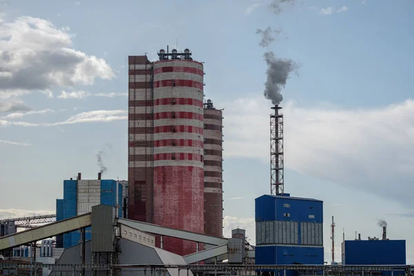 Vista de un complejo de edificios industriales con chimeneas humeantes en la tarde contra el cielo con nubes . — Foto de Stock