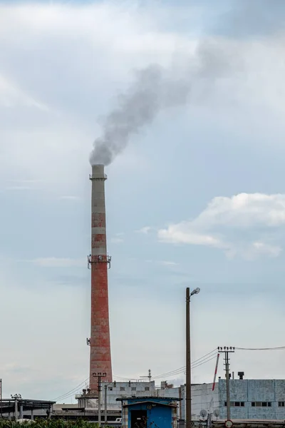 Vista de un complejo de edificios industriales con chimeneas humeantes en la tarde contra el cielo con nubes . — Foto de Stock