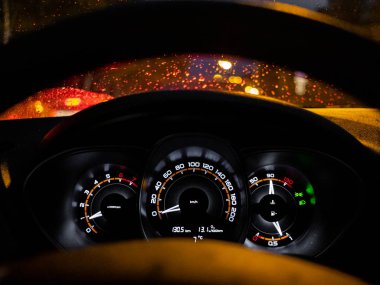 Sokak ışıklarının yansıması ön camüzerinde yağmur damlalarının arka plan karşı geceleri parlayan araba panosu.