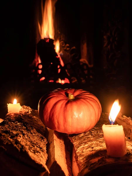 Хэллоуинская тыква в темноте на березовых бревнах рядом с горящими свечами. На заднем плане - пламя от камина . — стоковое фото