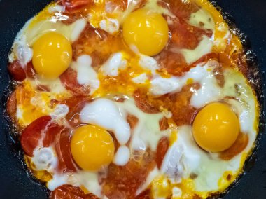 Sıcak tavada kırmızı domatesli taze pişmiş kızarmış yumurta. Lezzetli ev yemekleri..