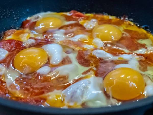 Свіжозварені апетитні смажені яйця з червоними солодкими помідорами на гарячій сковороді. Смачна домашня їжа . — стокове фото