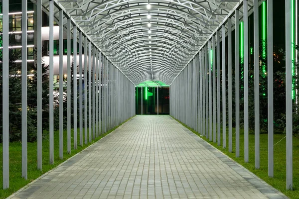 Футуристический пешеходный тоннель эстакады с ярким освещением, уходящий вдаль ночью. Городская геометрия . — стоковое фото