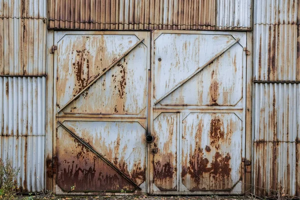 Geschlossen alten rostigen Eisentor Flügel in einer Wellblechwand. Industriebau aufgegeben. Grunge — Stockfoto