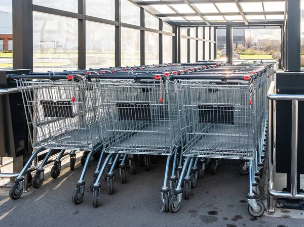 Rzędy wózków sklepowych z systemem płacy. Atrybut supermarketu i supermarketu w metropolii. — Zdjęcie stockowe