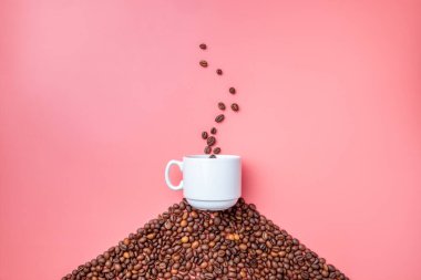 Düz yatıyordu. Beyaz bir seramik fincan pembe bir arka planda kahve çekirdekleri tepesinde duruyor. Kahve çekirdeği şeklindeki bir fincandan çıkan simüle edilmiş buhar. Kahvaltıda güzel kokulu kahve. Boşluğu kopyala.