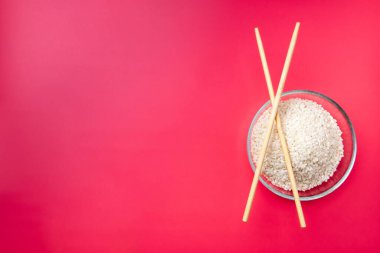 Düz yatıyordu. Pembe arka planda pilav ve çubuklarla şeffaf cam kase..