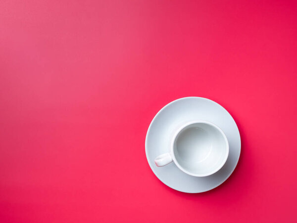 Flat lay. Empty white cup on a saucer on a pink background. Copy space