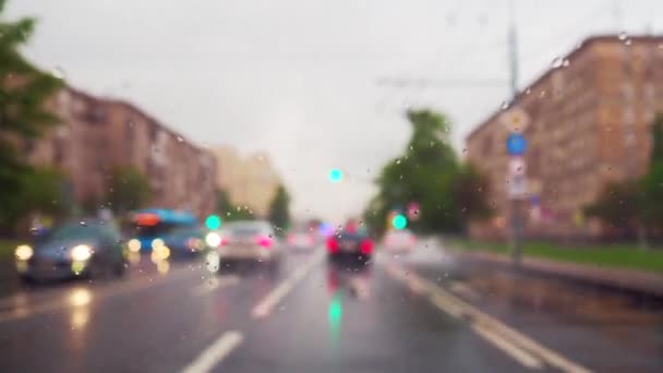 街の通りに沿って移動する乗用車のフロントガラスに雨滴に選択的な焦点 小さな滴が車のガラスに落ち ワイパーブレードによって洗い流されます — ストック動画